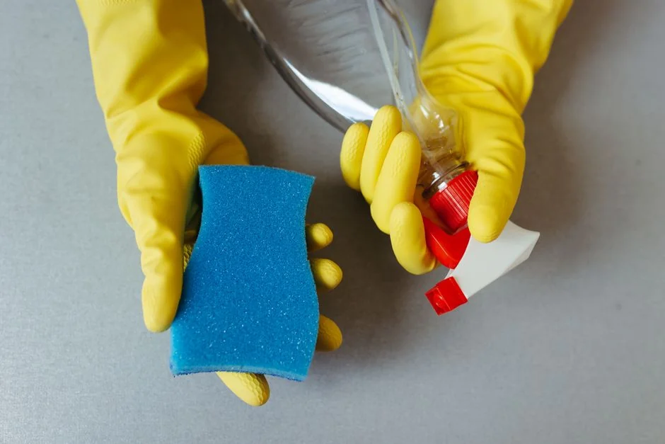 Homme anonyme portant des gants en caoutchouc jaunes, essuyant la mousse d'un miroir rond dans une salle de bain