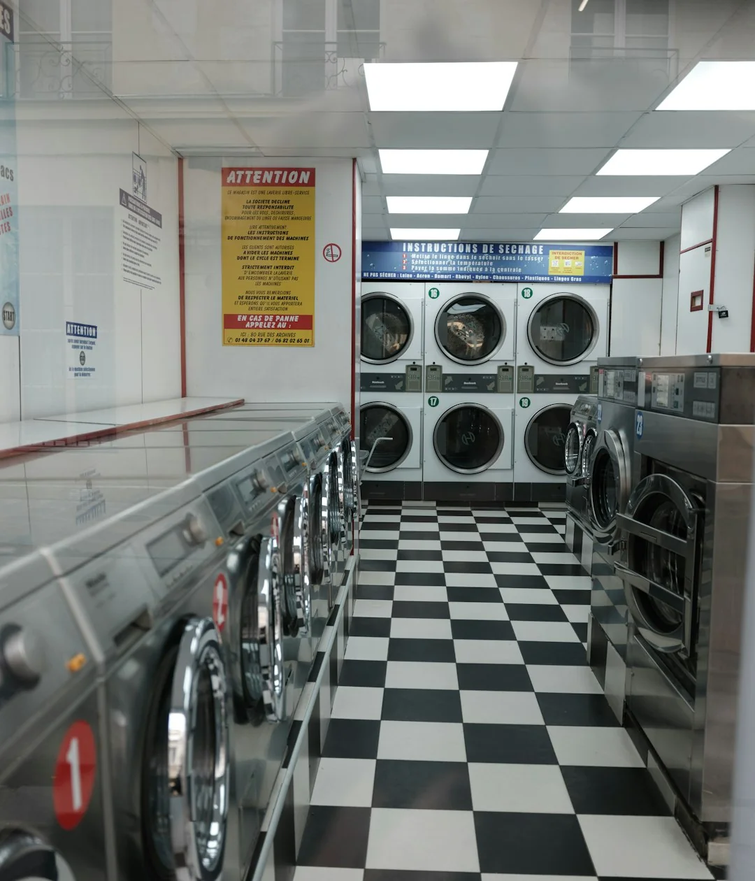 Équipe de nettoyage diversifiée en uniformes rouges, prête à désinfecter un salon moderne avec aspirateur et serpillière.